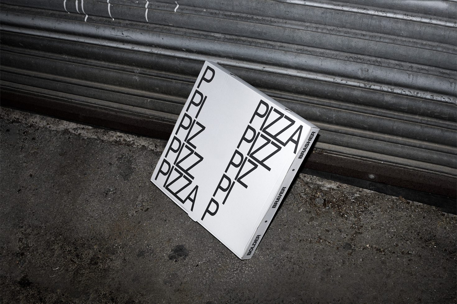 Pizza box packaging mockup with bold typography design on a gritty urban concrete floor for graphic presentations and portfolio display.